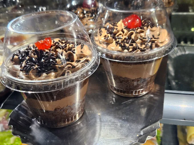 Bolos de pote de chocolate com granulado e cereja na vitrine